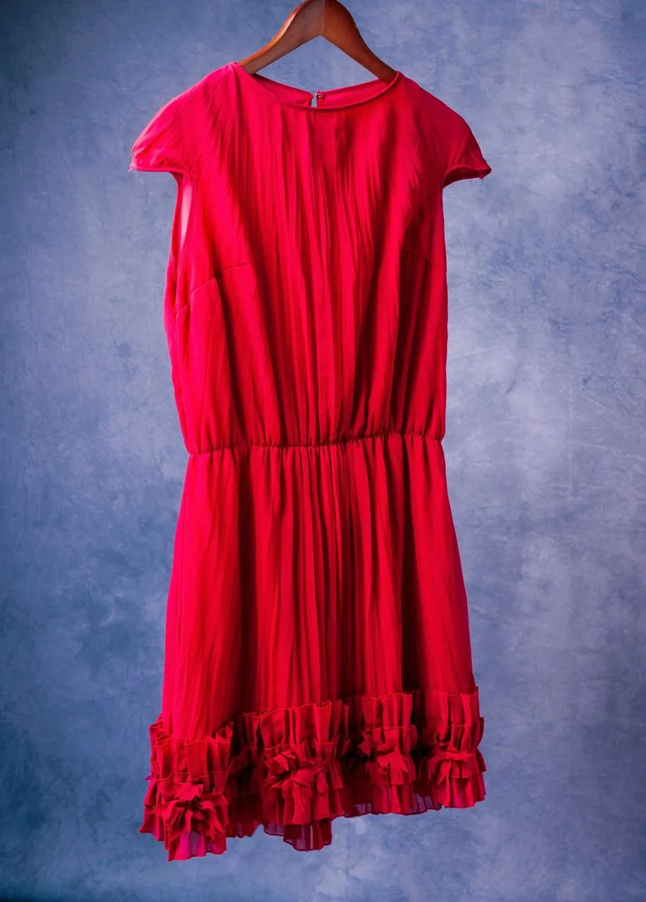 Vestido vermelho plissado com babados pendurado num cabide de madeira